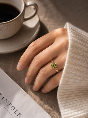 Aura Verdant Solitaire Ring featuring a brilliant round green crystal set on a gold-tone band with sparkling side accents.