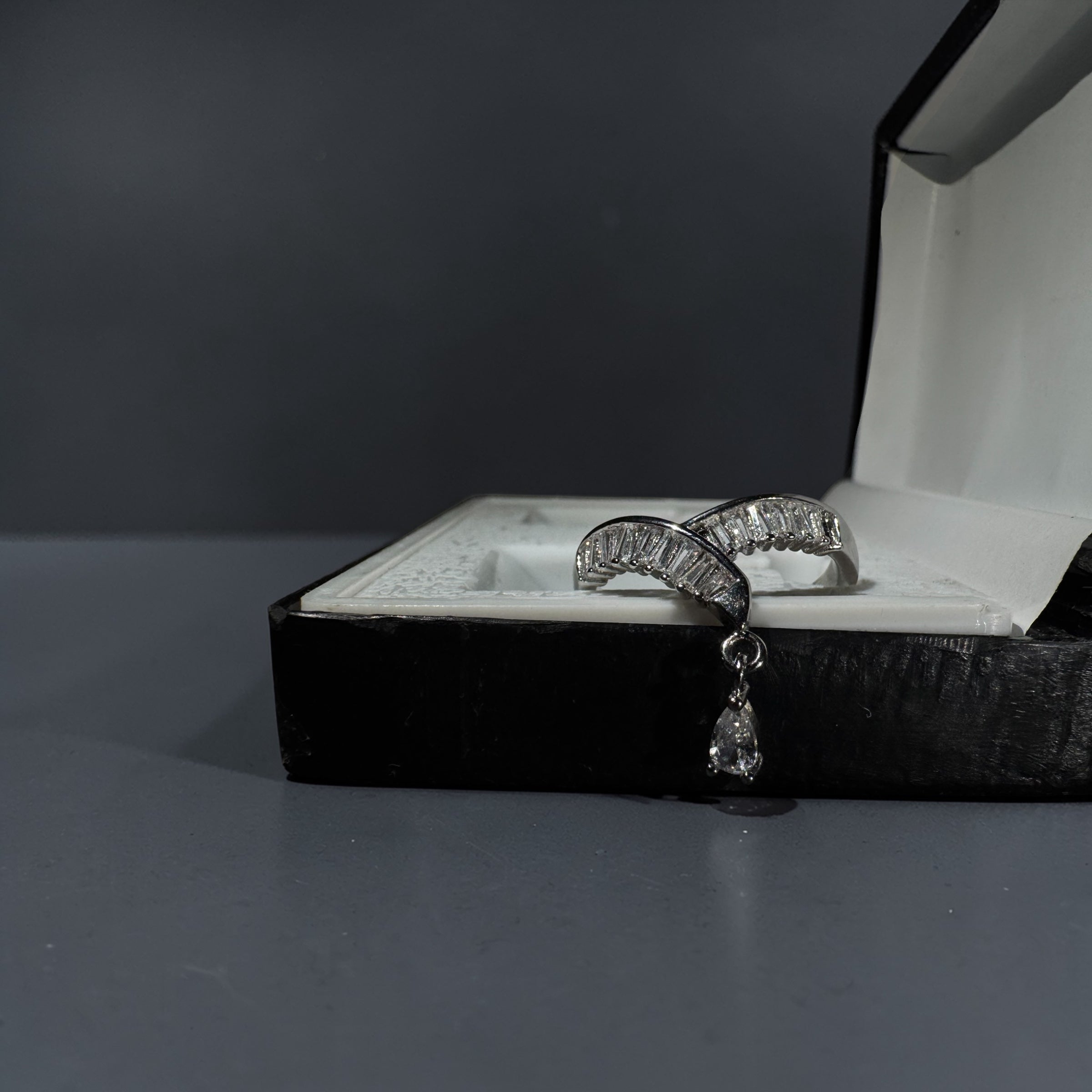 Silver stainless steel adjustable baguette crystal arc ring with dangling teardrop charm for women modern luxury jewellery Aura Collection