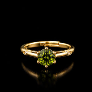 Aura Verdant Solitaire Ring featuring a brilliant round green crystal set on a gold-tone band with sparkling side accents.
